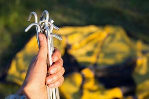 Aluminum stakes for the installation of a tourist yellow tent in the hand close-up. Lightweight equipment for tourism. Outdoor activities, assembly instructions, domestic ecotourism. Copy space photo