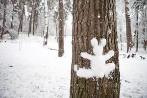 A snowman in the shape of a hare is stuck on the trunk of a tree. Fun winter activities and fun, children and family playing in the snow. Copy space photo