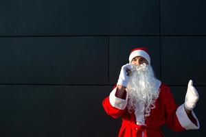 moderno santa claus hablando por teléfono. solicitando los servicios de un animador para navidad y año nuevo. saludos en línea a través de Internet y comunicación móvil, distancia social foto