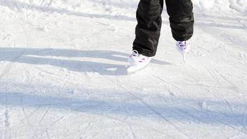 patines deslizantes de plástico para niños con primer plano de ajuste de tamaño sobre hielo en invierno al aire libre. rodando y deslizándose en un día helado y soleado, deportes de invierno activos y estilo de vida foto