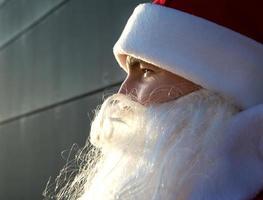 primer plano de la cara de santa claus sobre un fondo gris. brillo en los ojos, barba blanca, traje rojo con sombrero. navidad, año nuevo. helada del abuelo ruso. fondo moderno gris, espacios de copia foto