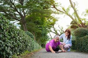 Asian senior woman fell down on lying floor because faint and limb weakness and Crying in pain form accident and her daughter came to help support. Concept of old elderly insurance and health care photo