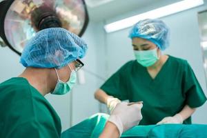 Asian Professional surgeons team performing surgery in the operating room, surgeon, Assistants, and Nurses Performing Surgery on a Patient, health care cancer and disease treatment concept photo