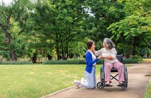 Asian careful caregiver or nurse taking care of the patient in a wheelchair.  Concept of happy retirement with care from a caregiver and Savings and senior health insurance, a Happy family photo