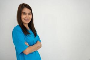 Portrait Of confident, happy, and smiling Asian medical woman doctor or nurse wearing blue scrubs uniform over isolated white background photo