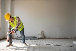 Construction worker Using an electric jackhammer to drill perforator equipment making holes before pouring the floor to be strong at construction site, Concept of worker and residential building. photo