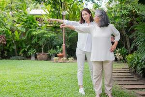 An old elderly Asian woman and exercise in the backyard with her daughter.  Concept of happy retirement With care from a caregiver and Savings and senior health insurance, Happy family photo