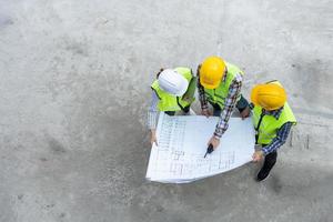 Top view of Asian engineer or Young Female Architect put on a helmet for safety and talk with a contractor on a construction building factory project, Concept of Teamwork, Leadership concept. photo