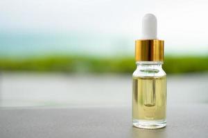 A glass bottle with dropper on the table. Concept of aroma oil, cosmetic, and beauty skin. photo