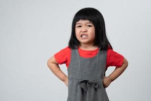 retrato de una niña asiática enojada y triste sobre un fondo blanco aislado, la emoción de un niño cuando berrinche y enojado, expresión de emoción gruñona. concepto de control emocional infantil foto