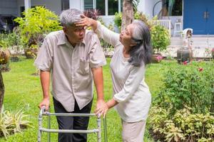 Happy old elderly Asian man uses a walker and walks in the backyard with him daughter and wife.  Concept of happy retirement With care from a caregiver and Savings and senior health insurance photo