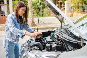 mujer asiática y usa teléfonos inteligentes para enviar imágenes del motor y enviar asistencia después de una avería del automóvil en la calle. concepto de problema o accidente del motor del vehículo, ayuda de emergencia de profesionales foto