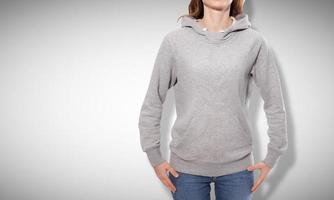 Shirt design and fashion concept - young woman in gray sweatshirt, gray hoodies, blank isolated on grey background photo