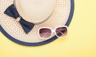 Summer hat with ribbon and sunglasses isolated on colorful background. Top view and copy space. photo