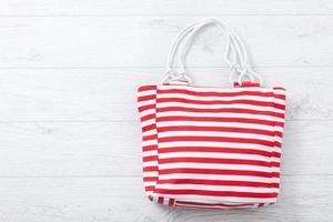 Summer accessories hat and bag on white wooden background. photo