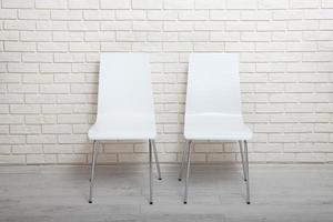 White chairs near the white wall for interior or graphic backgrounds. The chairs can be used to represent interview sessions or waiting rooms for ads purpose. photo