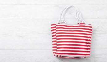 Summer accessories hat and bag on white wooden background. photo