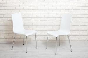 White chairs near the white wall for interior or graphic backgrounds. The chairs can be used to represent interview sessions or waiting rooms for ads purpose. photo