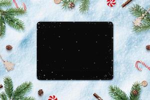 Tablet in snow for app design or copy promotion. Surrounded by Christmas decorations. Top view, flat lay photo