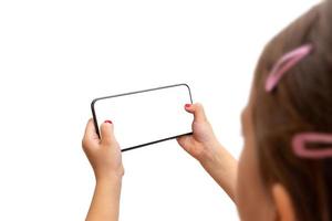 Little girl holding smart phone in horizontal position. Isoalted display and background. Playing game or watch video concept photo