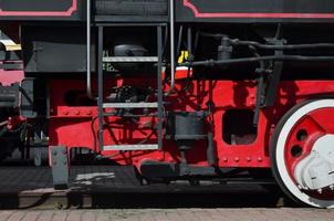 ruedas de la vieja locomotora de vapor negra de la época soviética. el lado de la locomotora con elementos de la tecnología giratoria de trenes antiguos foto