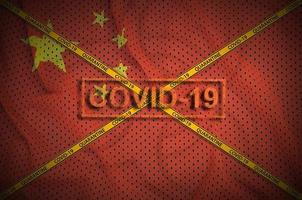 China flag and Covid-19 stamp with orange quarantine border tape cross. Coronavirus or 2019-nCov virus concept photo