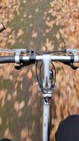 View of the steering wheel of a moving bicycle in an autumnal landscape with lots of leaves video