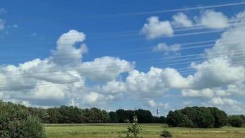 View from the side window of a moving car at big power pylons and power lines while driving on a country road in Germany video