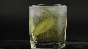 shot de tequila mexicaine dorée avec citron vert et sel sur fond noir. un verre de tequila avec des tranches de citron et des éclaboussures. concept de boisson alcoolisée. mise au point sélective. video