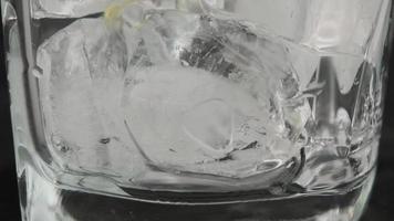 primer plano de cubitos de hielo cayendo en un vaso transparente vacío. video