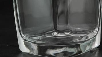primer plano de cubitos de hielo cayendo en un vaso transparente vacío.