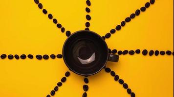 stop motion de café noir dans une tasse avec des grains de café autour sur fond jaune, gros plan.