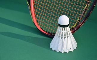 Cream white badminton shuttlecock and racket on floor in indoor badminton court, copy space, soft and selective focus on shuttlecocks. photo