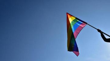 Rainbow flag holding in hand against bluesky background, concept for LGBT celebration in pride month, June, around the world. photo