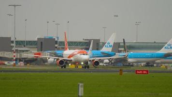 amsterdam, il Olanda luglio 27, 2017 - airbus a320 di easyjet cavalcate su il taxiway per il pista di decollo a schipol aeroporto, amsterdam. nel il sfondo, il aerei di il linea aerea klm. video