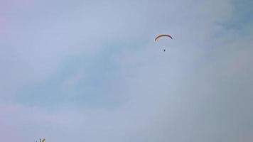 Paraglider soaring against the backdrop of a sunny blue sky. Bottom view video