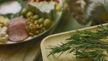 charcutaria plana com salame, diferentes tipos de queijo. tem frutas secas, nozes diversas e mel. arranjo de férias com velas acesas video