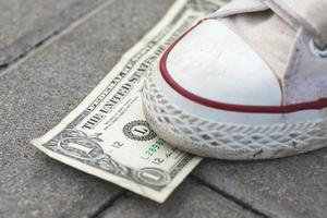 Female foot and one dollar banknote on the ground photo