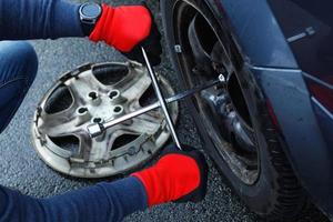 Man changing flat tire on his own car photo