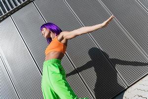 Carefree woman dancer wearing colorful sportswear having fun on the street during summer sunny day photo