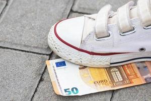 Female foot and five euro banknote on the ground photo