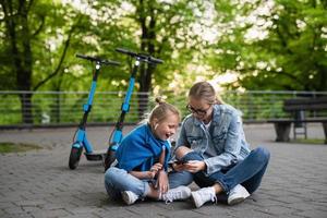 madre e hija usando una aplicación en un teléfono inteligente para compartir scooters eléctricos foto