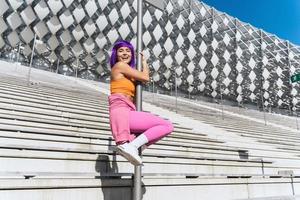 Carefree woman dancer wearing colorful sportswear having fun on the pole photo