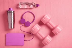 Dumbbells, headphones and protein shaker on the fitness mat photo