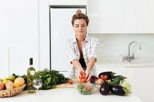 mujer cocinando un plato vegetariano saludable en casa en una cocina blanca foto