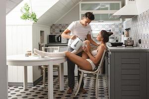 joven pareja feliz durante el desayuno en la acogedora cocina foto