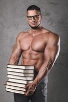 Smart and muscular man with a heap of books photo