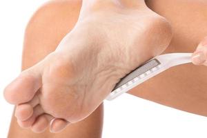 Closeup of female feet and callus remover tool photo