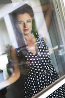 Gorgeous woman wearing beautiful dress with a polka dot pattern looking through the window photo