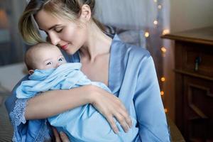 Young beautiful mother with her cute little baby wrapped in the blue cloth photo